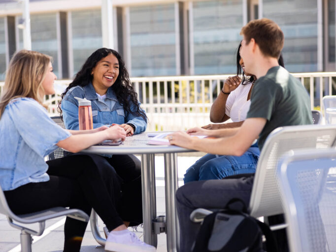20210504_UofU_4843_2000-682×532 some students chatting at a picnic table on campus