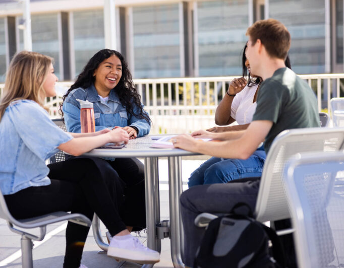 some students chatting at a picnic table on campus