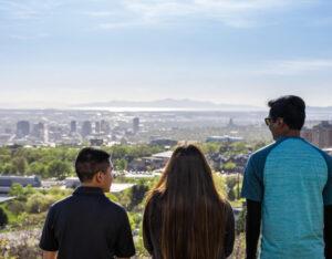 three students look out over the campus from one of the nearby mountains