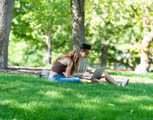a pair of students doing homework on a grassy field