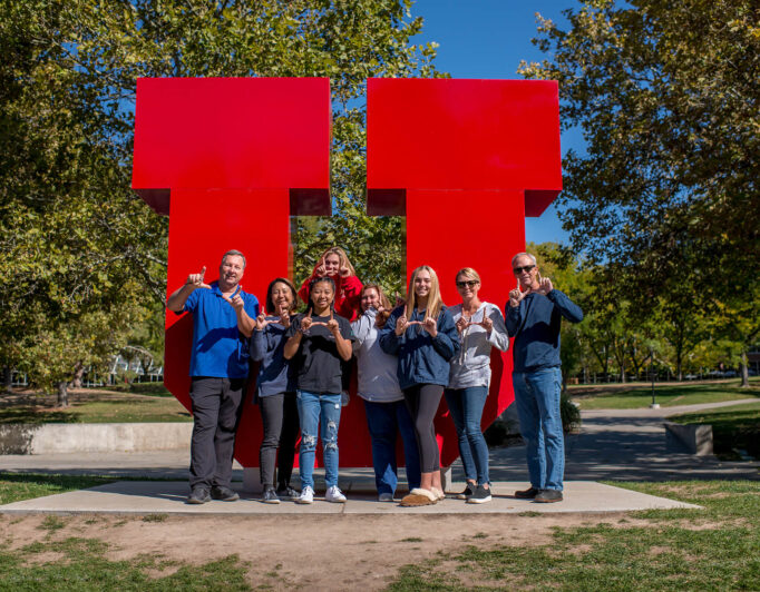 Trish-Griffee-Photography-7918-682×532 a group doing the U hand sign in front of the block U