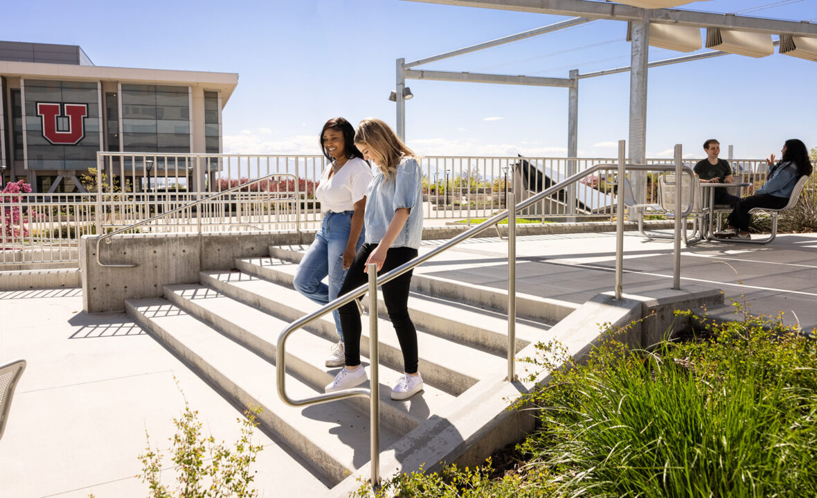 a couple of students talk as they walk down some stairs near the library
