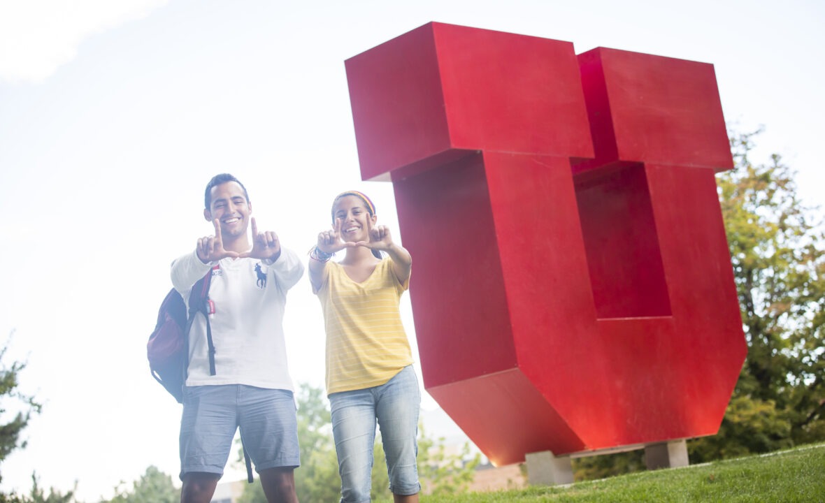a couple of students next to the block U doing the U hand sign