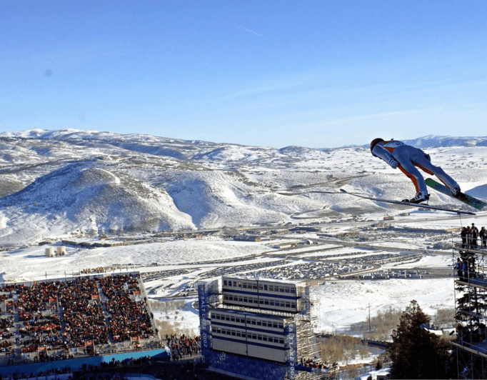 Utah-Olympic-Games-venue-blueprint-revealed-682×532 an Olympic skier mid-jump, with a crowd in the bleachers below