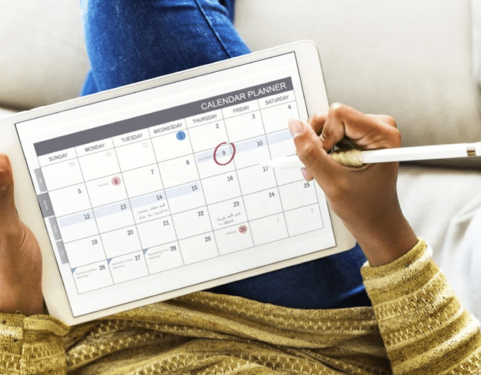 Woman-checking-calendar-682×532 someone working with a calendar on their tablet