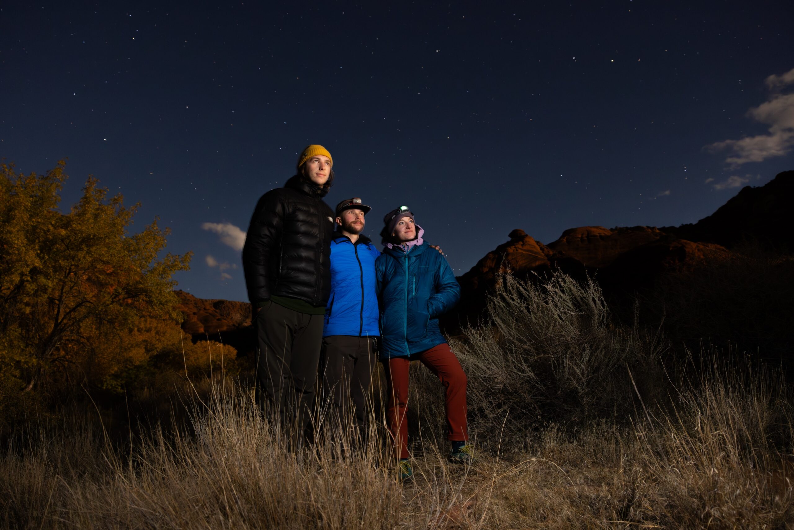 three students hanging out watching the sunset with the night sky behind them