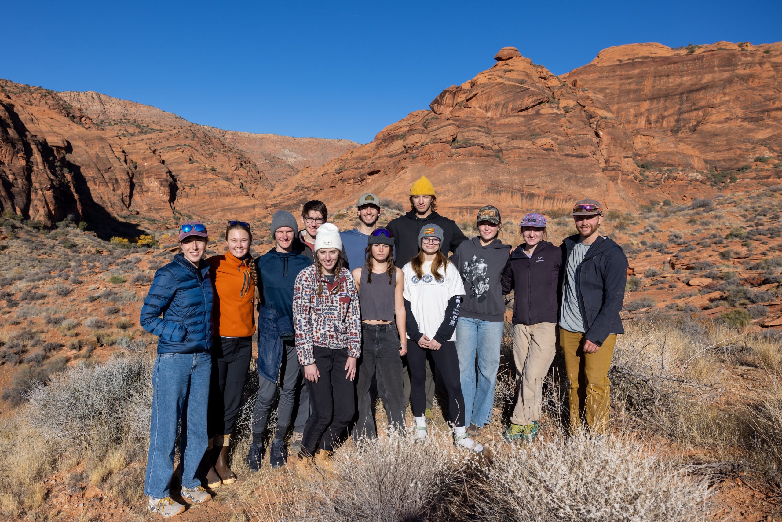 a group of several students pose in southern Utah with the red rocks behind them